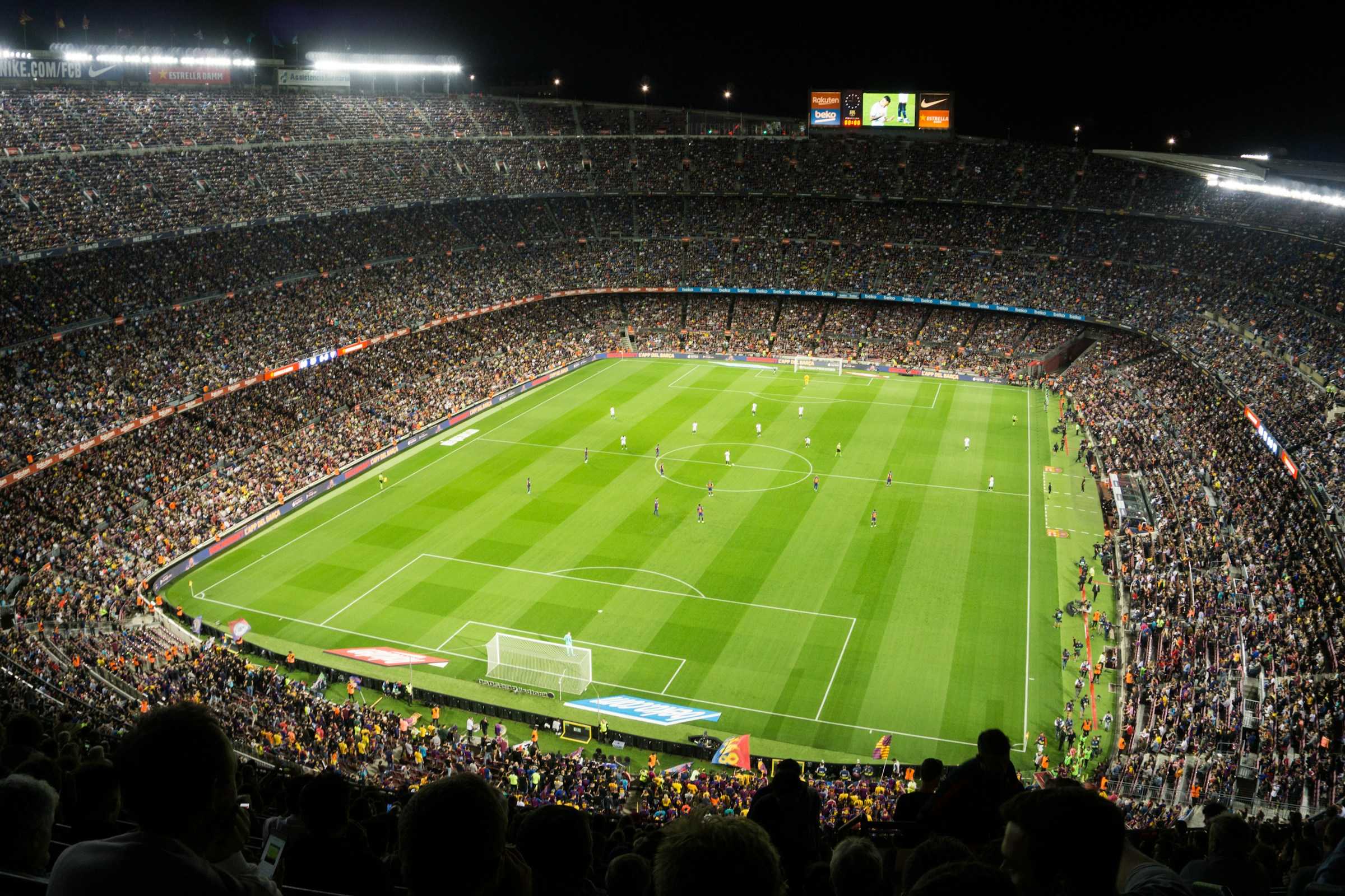 Elevated corner view of an illuminated football pitch surrounded by a packed stadium at night